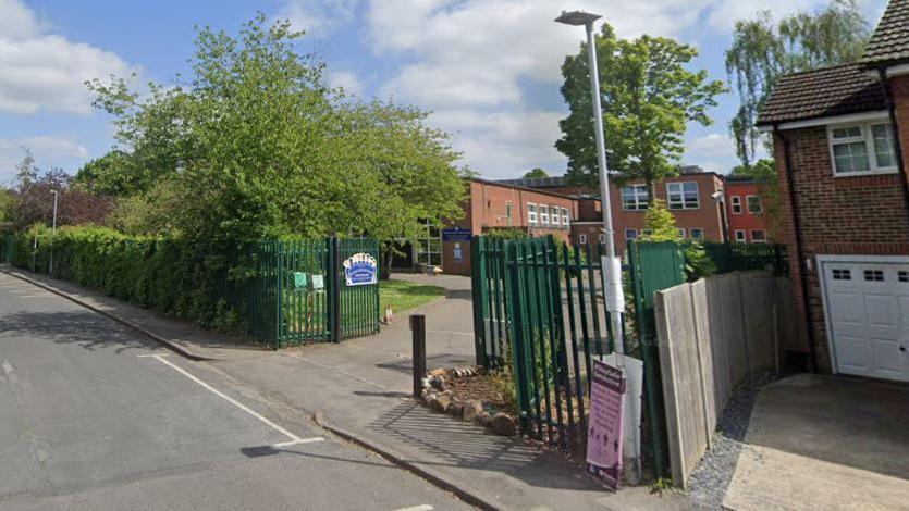 A school with green gates with a road outside