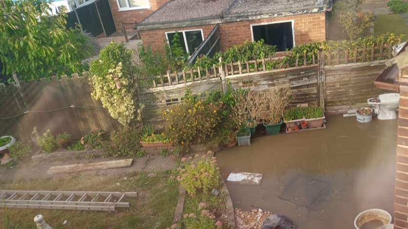 A view from a bedroom window of the brown water in the back garden of a house