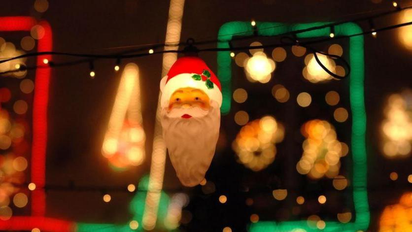 A Santa Claus Christmas light with a festive scene in the background.