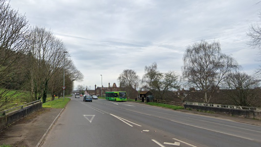 The A39 near Minehead seen from a Google street view image. Cars and buses are visible in the distance and trees are lining the road