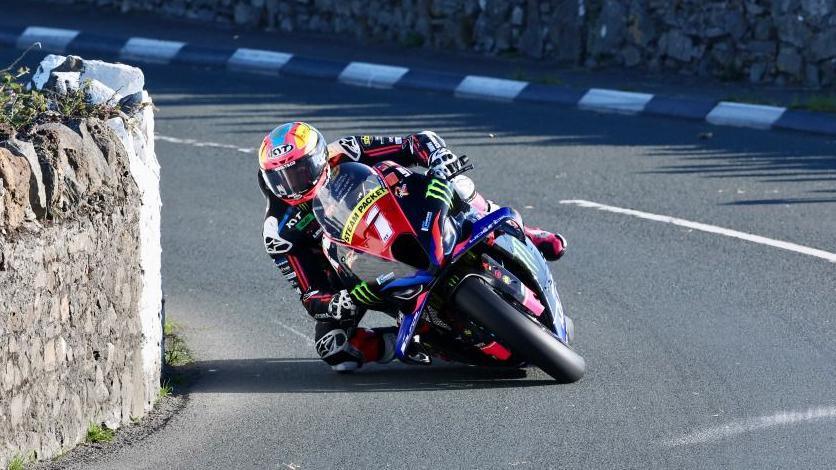 Davey Todd leaning towards a stone wall as he rounds a bend on the Billown Course.