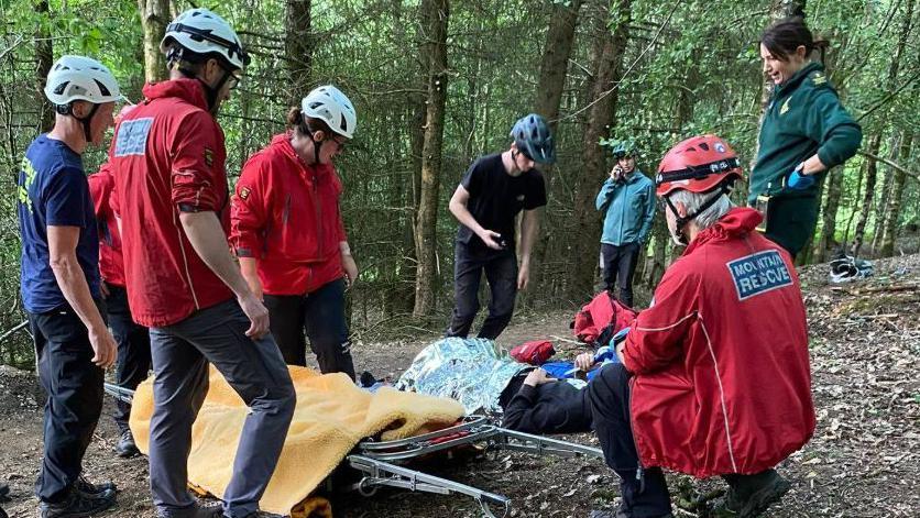 Casualty being placed on a stretcher with volunteers from the Rossendale and Pendle Mountain Rescue Team and a member of staff from the North West Ambulance Service in Lee Quarry.