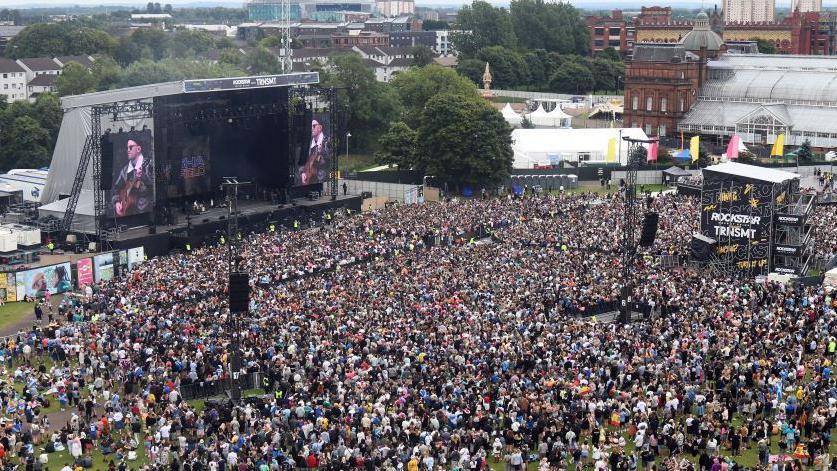 The main stage at TRNSMT music festival from a birds-eye view. The crowd stands in front of the stage and the People's Palace at Glasgow Green is on the right.