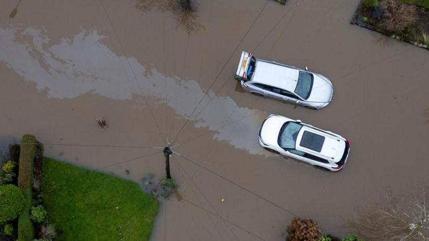 A drone shot of two cars left abandoned in brown flood waters 