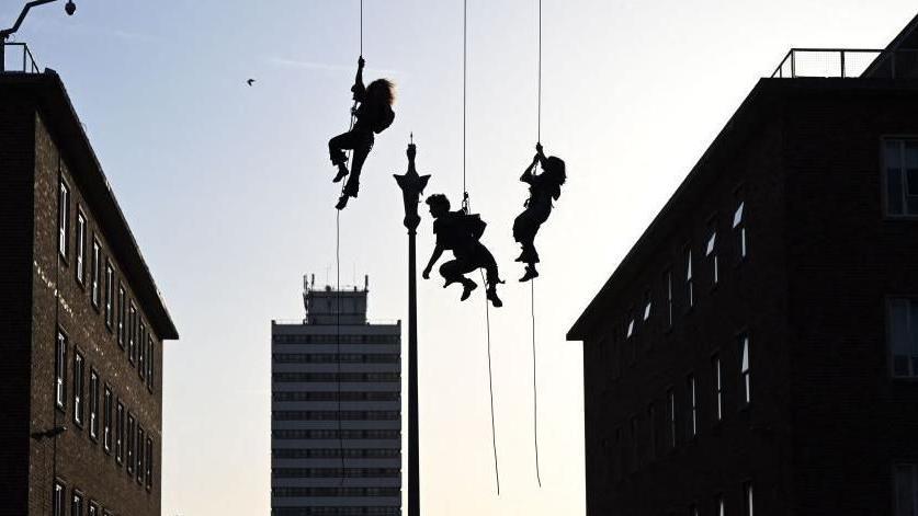 The silhouettes of three people abseiling in Coventry 