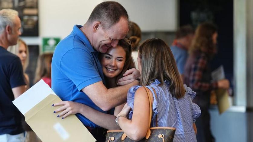 Lily Clancy with her parents as she receives her A-level results at Solihull School. Picture date: Thursday August 14, 202