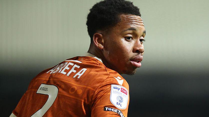 Kelvin Abrefa, in orange Reading shirt, facing away with his number and surname visible, turning his head towards the camera