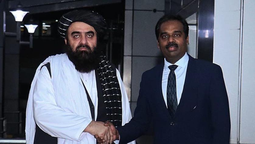Amir Khan Muttaqi shakes hands with an Indian diplomat