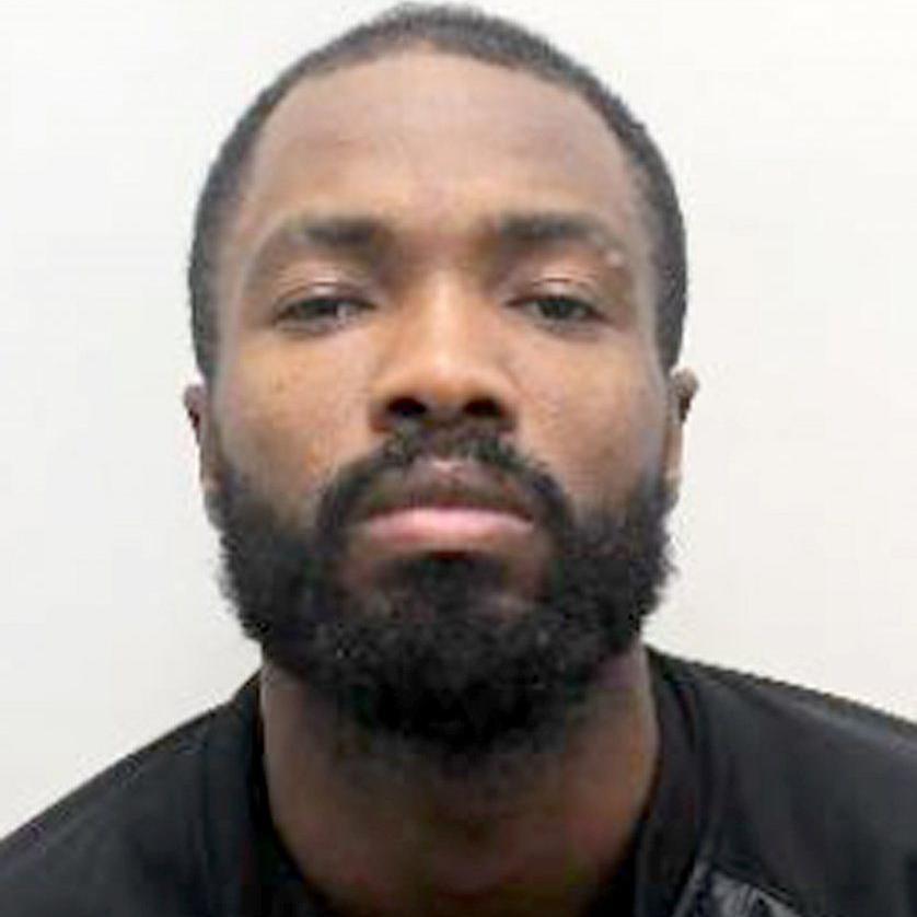A police custody shot of Javon Riley, he has short black hair and a beard and is wearing a black top 