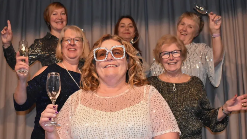 Members of Bleadon Women's Institute holding champagne glasses at the first daytime disco