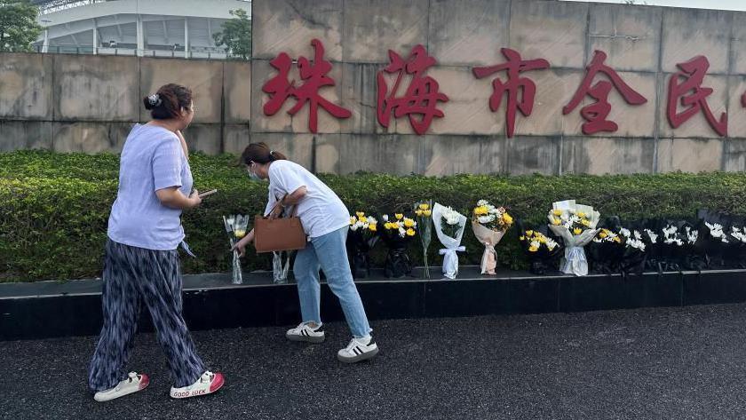 Women leaving flowers outside the Zhuhai sports centre