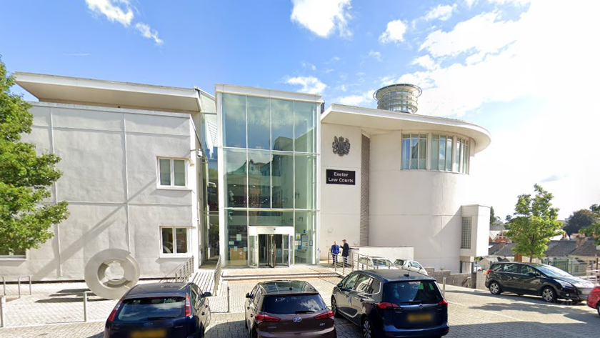 A picture of the front of Exeter Crown court. It is a white building with cars parked outside the front of it.