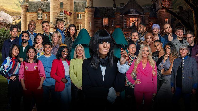 A group of 25 smiling contestants standing with Claudia Winkleman and two hooded figures at their centre, against a backdrop of the castle in which the series is based.