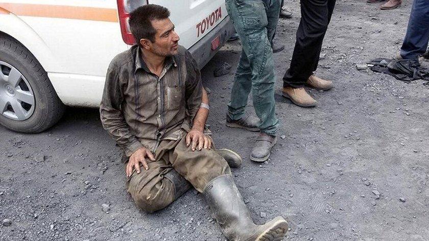 A man sits with his back against a van after the explosion in a coal mine in northern Iran