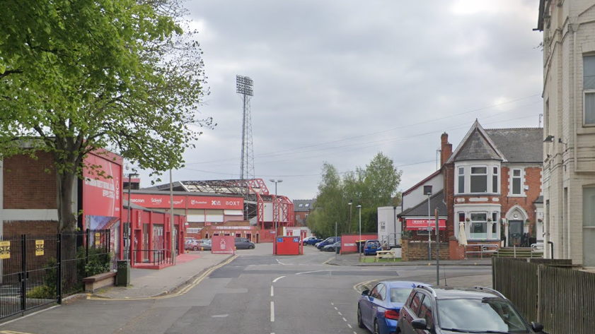 Cars in the street with Nottingham Forest's football ground in the background