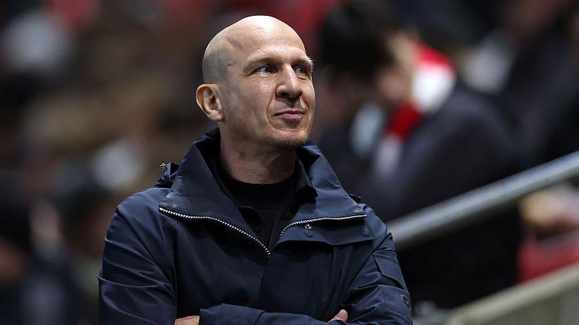 Bristol City boss Gerhard Struber smiles and looks up at the stands while folding his arms on the touchline