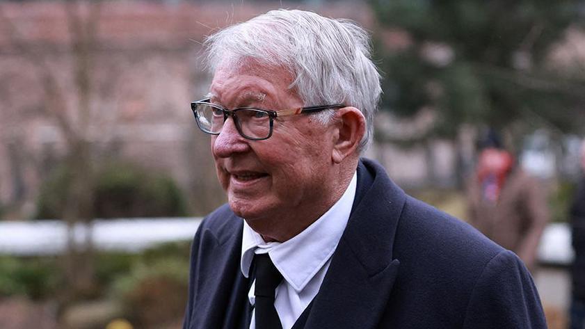 Sir Alex Ferguson with grey hair and black glasses arrives at Manchester Cathedral