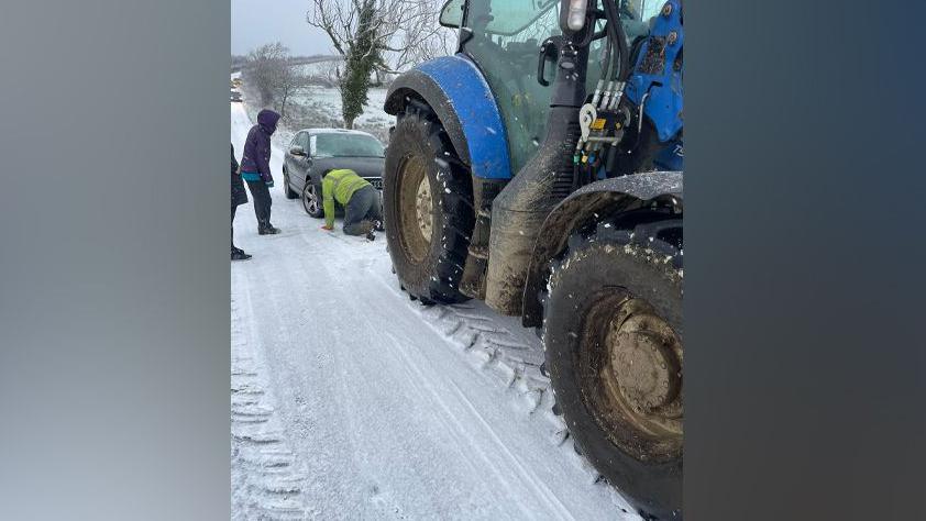 Tractor rescuing car from snow