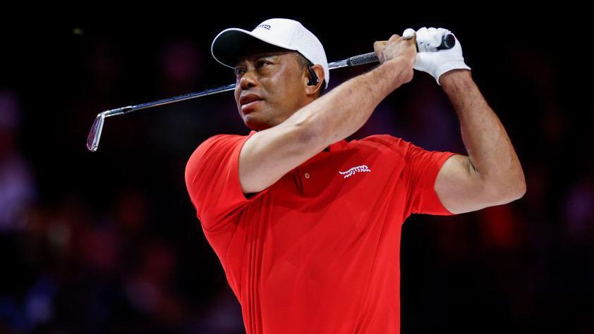 Tiger Woods watches his ball after an iron shot