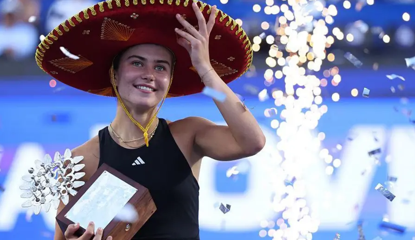 Iva Jovic stands on court holding the Guadalajara Open trophy