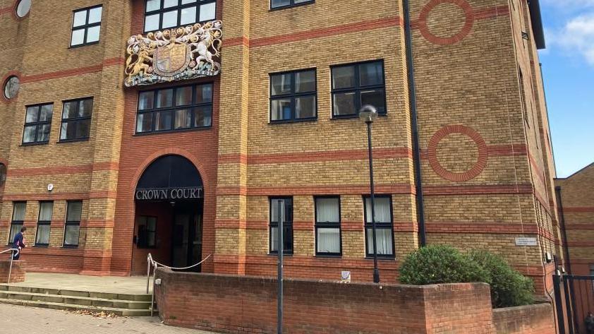 St Albans Crown Court: A red and yellow brick building. The words CROWN COURT are written in silver capitals above the entrance.

