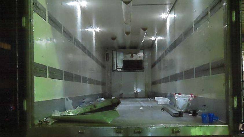 The back of a large lorry with debris scattered across the floor.