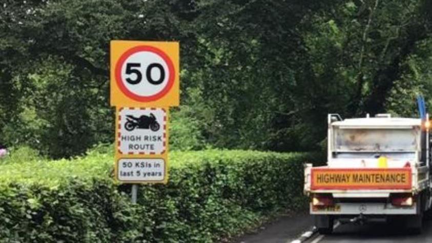 A 50mph road sign next to the back of a highways maintenance truck