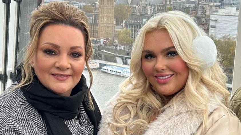 Breege Gormley has dark blonde hair and is wearing a black scarf and grey overcoat. She is pictured with her daughter Jenny on the London Eye. 
Jenny has bright blonde hair and is wearing white earmuffs and a white jacket. 