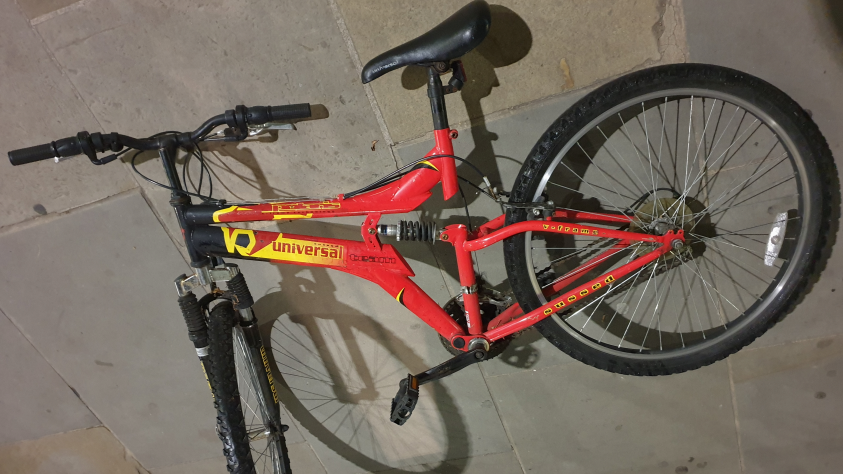 A bike with a red frame is laid out on the pavement.