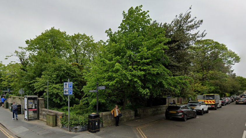 A general view of the corner in St Andrews where the proposed public garden would be built. It is almost completely obscured by large trees on either side.