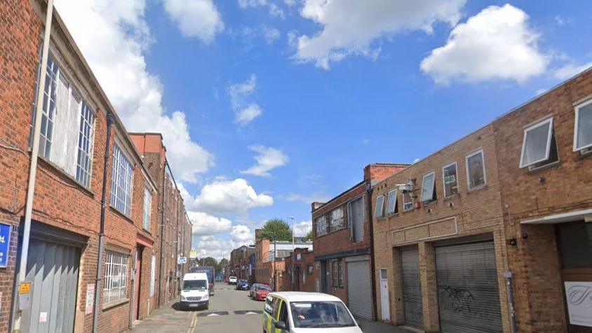 A Google street view photo of a road with factories on 