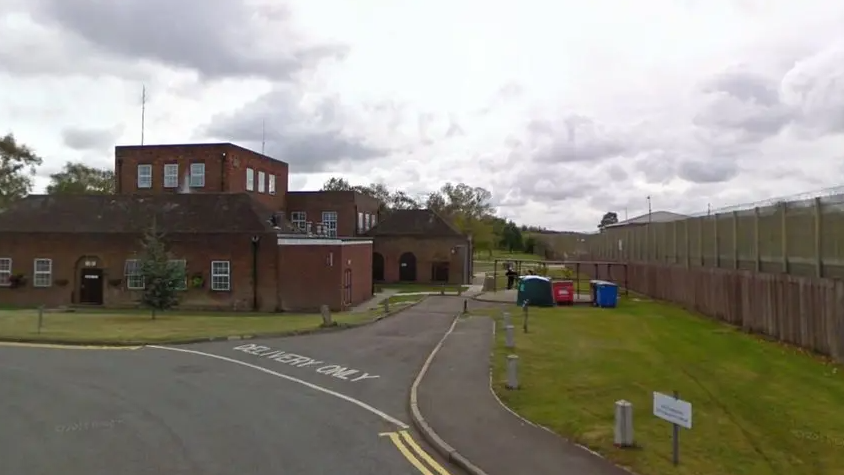 Exterior of prison with high wire fence on the right and standard block buildings
