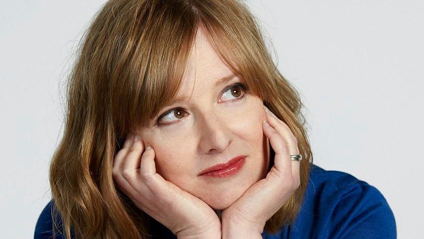 A close-up photo of writer Lucy Mangan with chin resting on her hands looking up to her left