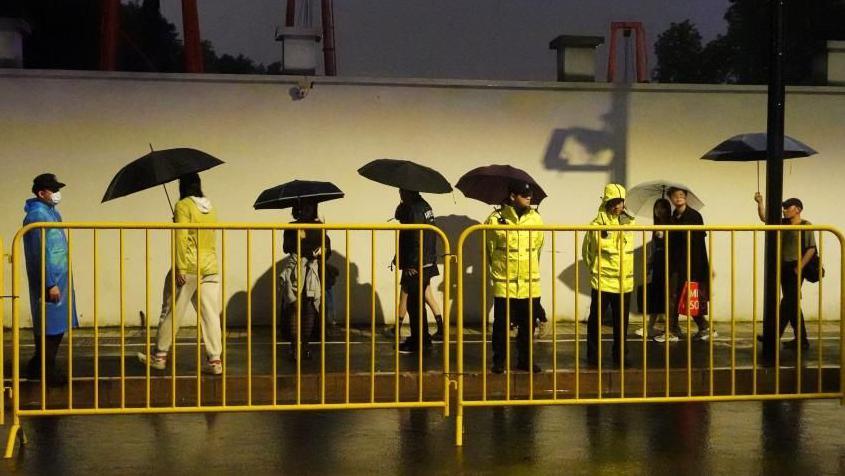 Police keep watch near barricades set up along a road in Shanghai during Halloween week