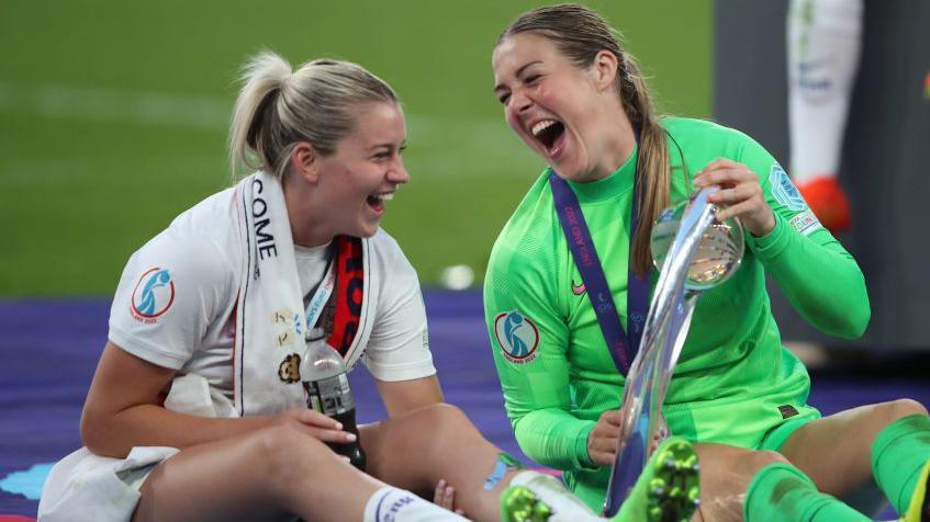 Mary Earps and Alessio Russo celebrate on the Wembley pitch with the Euro 2022 trophy