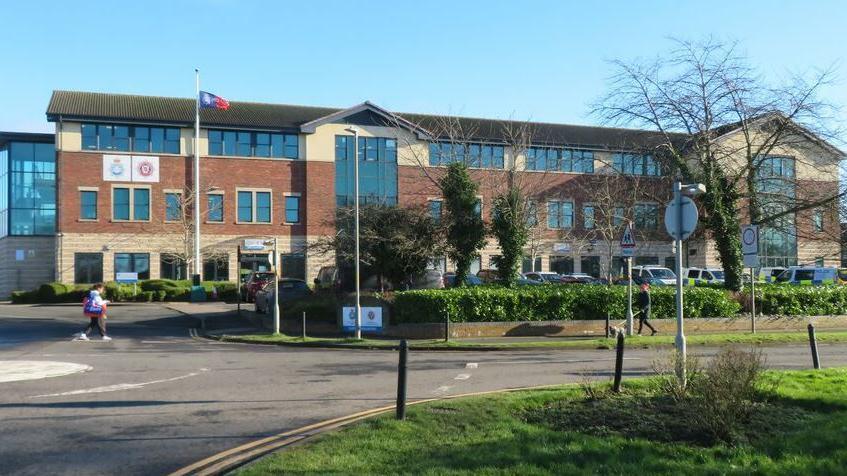 North Yorkshire Police HQ, a large red-brick building with police badges on the walls and a flag flying.