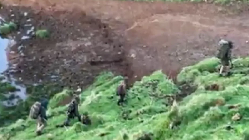 Phillips and his three children, in this blurry image, seen wearing camouflage uniforms and carrying large backpacks, trek through green bush with bare earth and some water visible