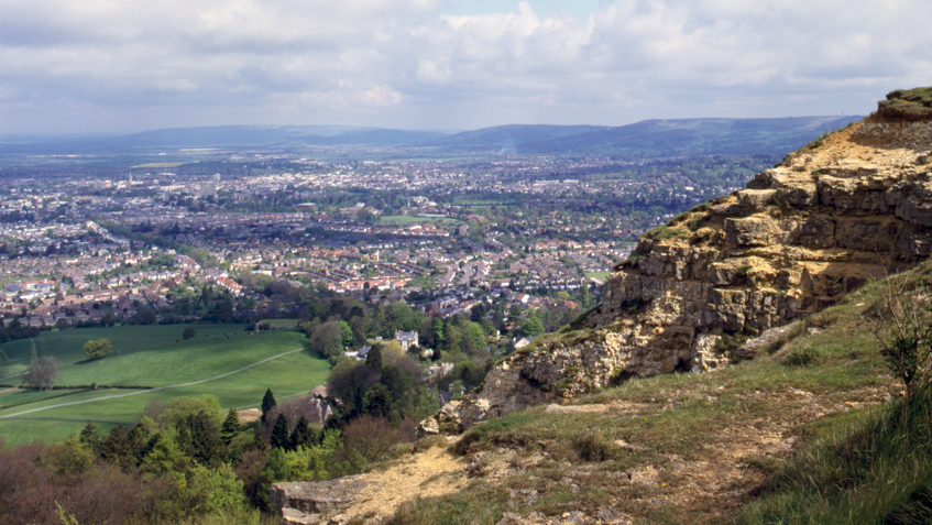 A rock formation with many homes in the background of a wife landscape