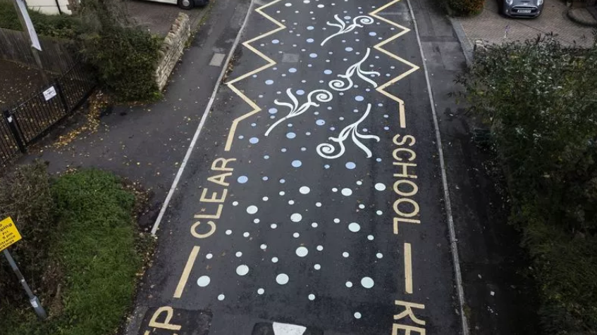 A road painted with 'School keep clear' markings on each side with dots and squiggles in between