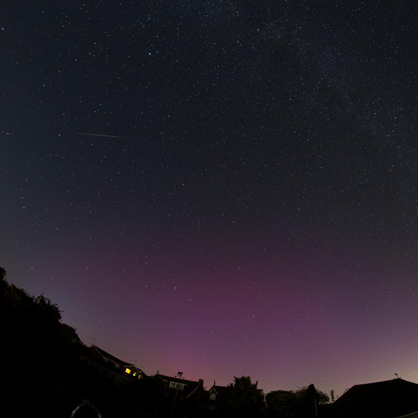 A black and purple sky littered with stars. In the top left, a meteor can be seen shooting across the sky.