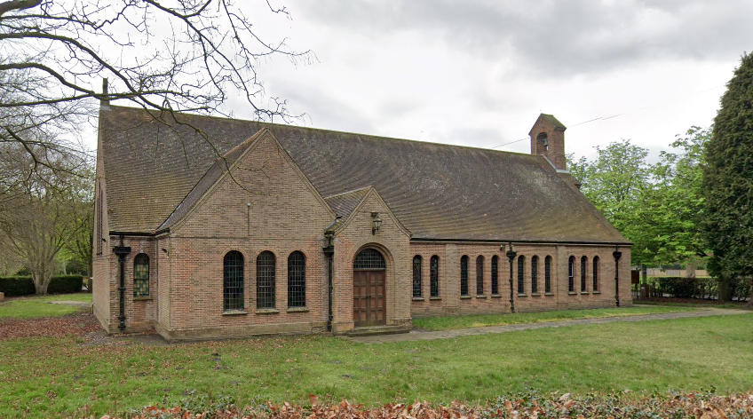 A one-storey church, with grass, leaves and trees.