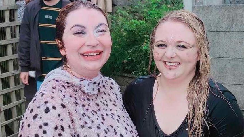 Two competitors in the World Gravy Wrestling Championships, one dressed as a Dalmatian and the other in a black T-shirt, smile at the camera