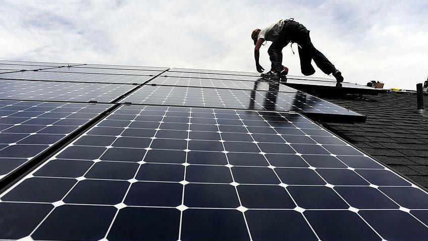 A man installing solar panels on a roof