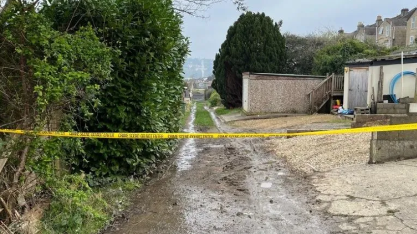 A strip of yellow police tape is seen stretched across a lane in Bath. 