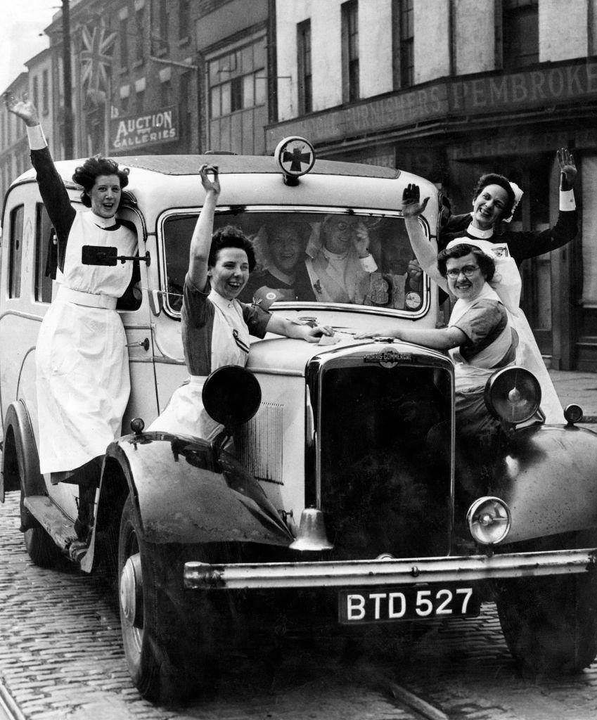 Nurses on a car waving