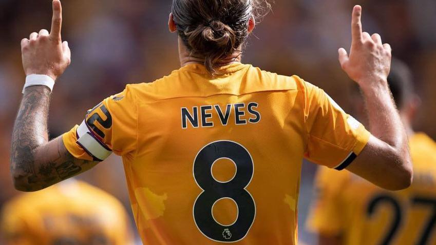 A footballer, fingers pointing skywards, with the name Neves and the number eight on the back of his old gold shirt