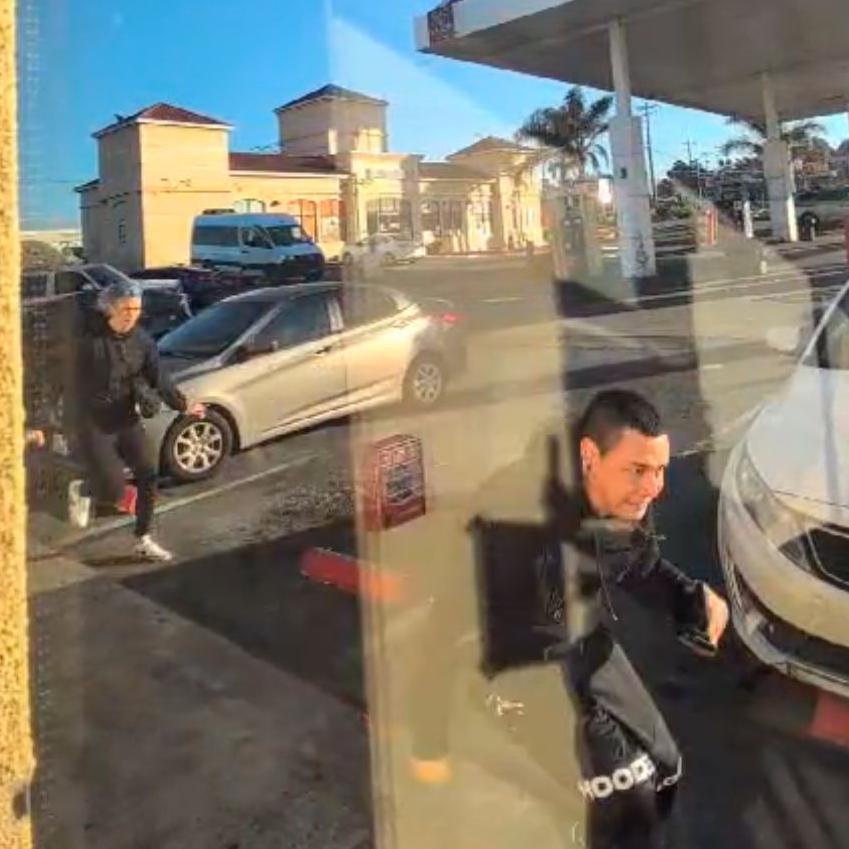 A still image from a video showing the robbery of British band Sports Team while on tour in the US. Two crouched figures can be seen running away from the scene. In the background, you can see their tour van with it's door open. A man is just out of shot, behind the door, apparently looting the vehicle.