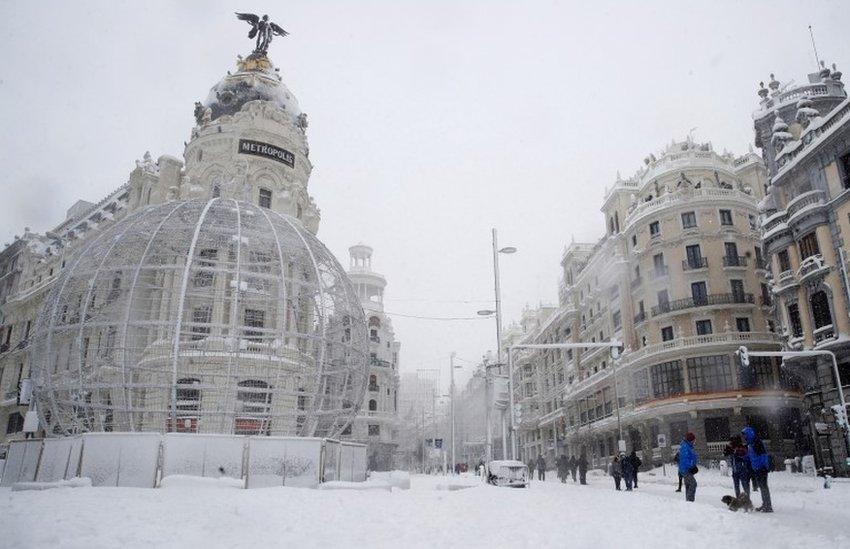 People walk along a snow-covered Gran Via in Madrid, Spain.