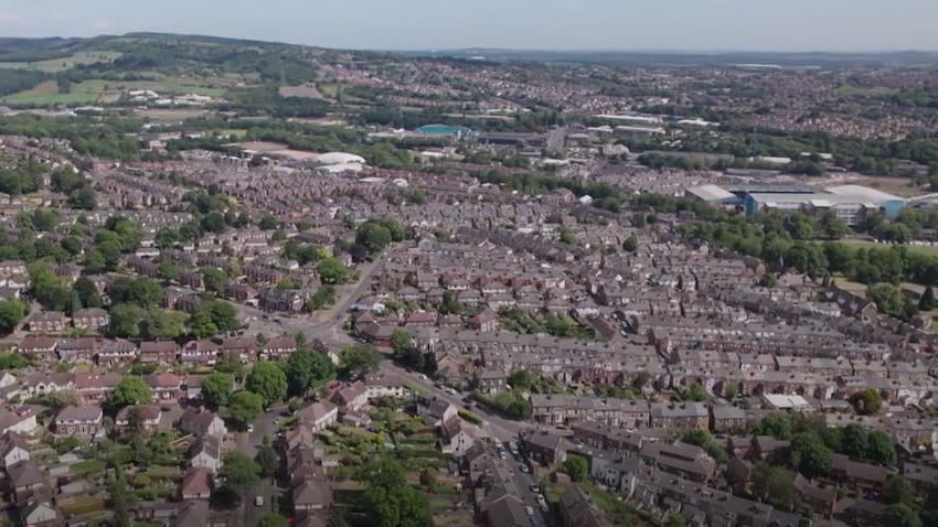 An aerial picture of Sheffield showing rows of houses and factories surrounded by trees and green spaces.