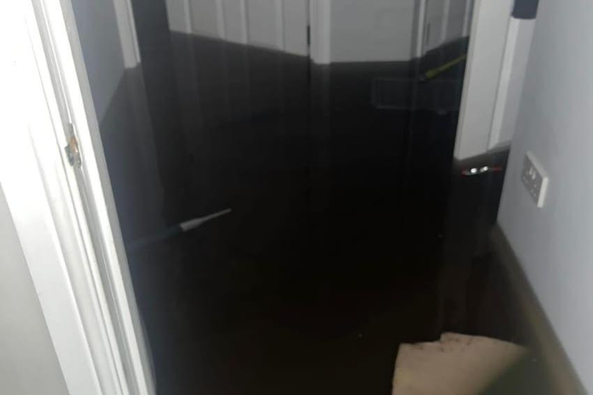 The hallway of Ed Clarke's flat, with white door frames and doors, with several feet of flood water inside it